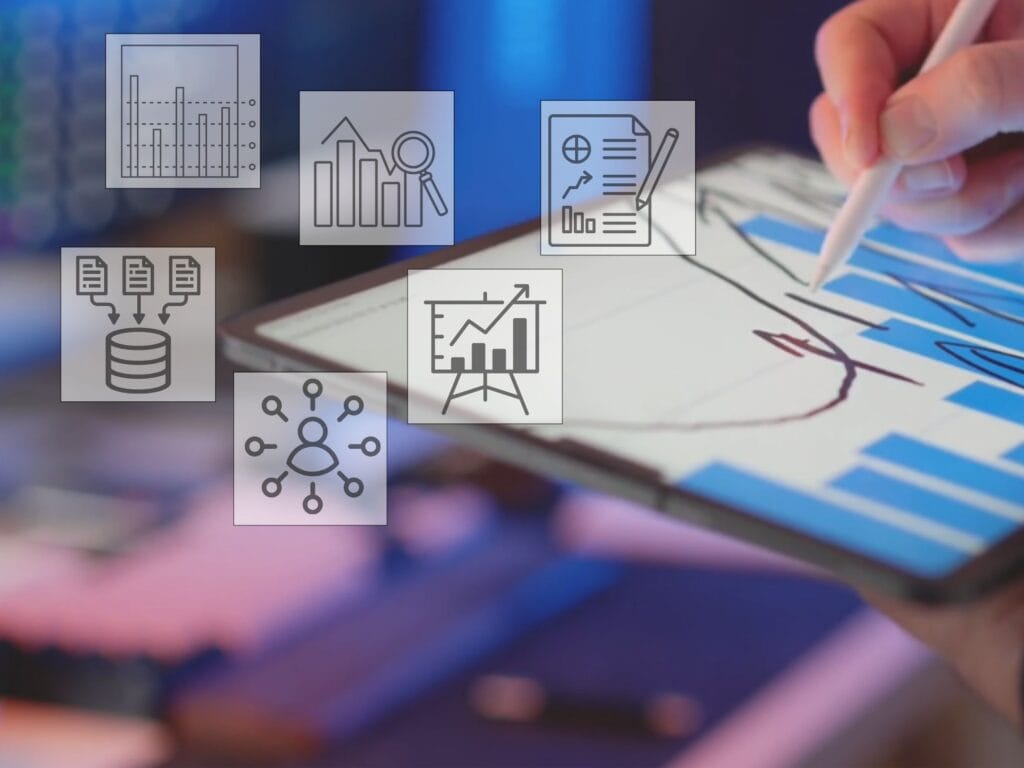 Eine Hand zeichnet mit einem Stift eine Kurve auf einem Tablet mit Balkendiagramm, umgeben von Analytics-Icons.