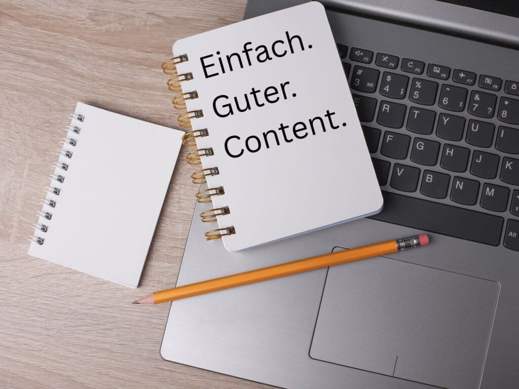 Ein geöffneter Laptop auf dem ein Notizblock mit der Aufschrift Einfach. Guter. Content. und ein Bleistift liegen.